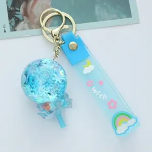Blue acrylic oil-filled lollipop keychain with shiny sequins and a decorative 'wish' strap