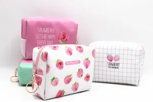 Primer plano de bolsas de cosméticos impermeables con estampado de fresas y aros.