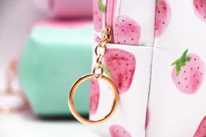 Detalle de neceser con estampado de fresas, cremallera dorada y tirador.
