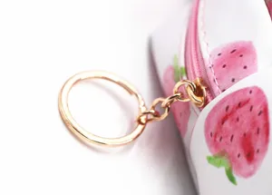 Detalle de la cremallera rosa y el anillo dorado en el neceser con estampado de fresas