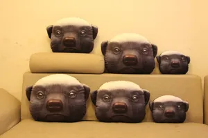Vista de cojines de peluche 3D de cabeza de tejón en varios tamaños en sofá