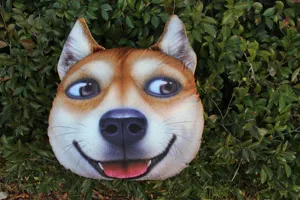 Primer plano de un divertido cojín de peluche 3D con cabeza de perro Shiba Inu en hojas