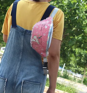 Vista detallada de la riñonera de lentejuelas rosas con unicornio usada por una niña fuera.