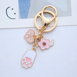 Macro detail of a cute pink cat paw and sakura cherry blossom charm on a gold keychain