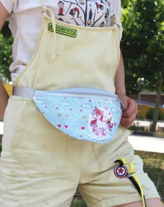 Detalle de una riñonera de unicornio con lentejuelas azules y un peto amarillo.