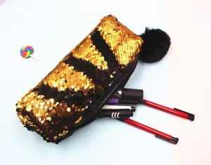 Primer plano de un estuche de lentejuelas reversibles en oro y negro con un pompón.