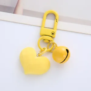Close-up detail of a vibrant yellow heart-shaped keychain with a matching bell