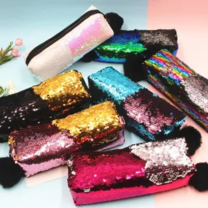 Estuches de lentejuelas reversibles con pompones negros sobre fondo rosa y azul claro.