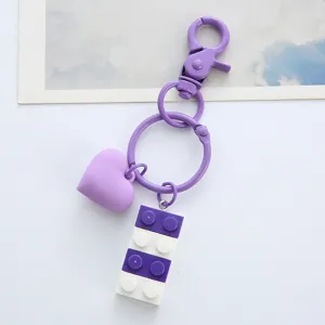 Macro view of a purple heart and building block keychain featuring a purple metal clasp.