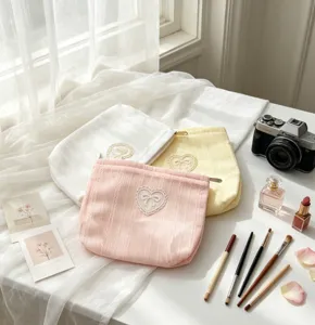 Pastel bow makeup bags with heart lace detail and cosmetics on a white surface.