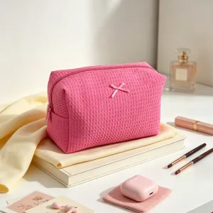 Primer plano del neceser de maquillaje rosa con textura de gofre y un lazo decorativo.