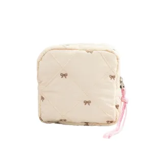 Quilted cream cosmetic storage pouch with bow embroidery and pink rope zipper pull handle