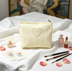 Elegant cream bow makeup bag featuring heart lace detail and soft ribbed texture