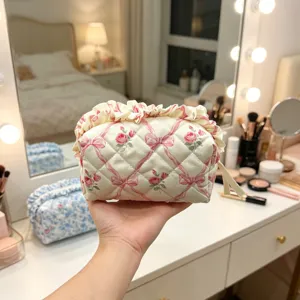 Nahaufnahme einer gesteppten Blumenkosmetiktasche mit Rüschen und Rosenmustern.