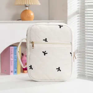 Detailansicht der gesteppten Buchhülle in Creme mit schwarzer Schleifenstickerei
