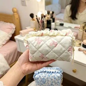 Detailansicht einer weißen gesteppten Kosmetiktasche mit rosa Schleifen und Rüschen
