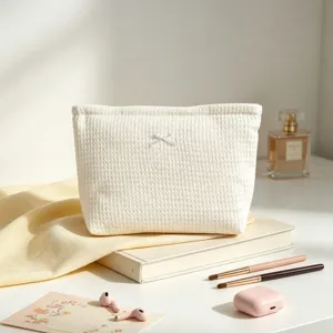 Elegante neceser blanco con textura de gofre y lazo sobre un escritorio moderno