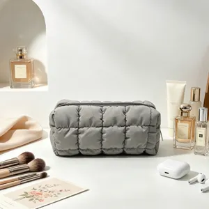 Detalle del neceser acolchado gris que presenta una textura suave tipo nube