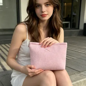 Vista detallada de una bolsa de cosméticos de punto gofre rosa con lazo por modelo