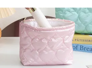 Detalle del neceser de maquillaje acolchado corazón rosa guardando productos cosméticos