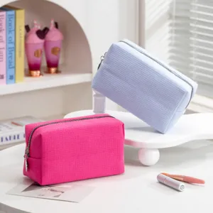 Detailopname van wafelstructuur cosmetische tassen in levendig roze en lichtblauw