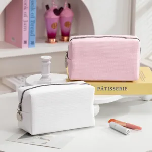Detailweergave van de wafelstructuur van roze en witte make-uptasjes op een kaptafel-decor