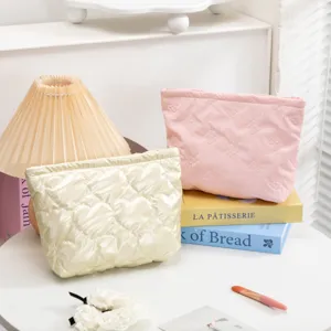Bolsas de cosméticos acolchadas con corazones crema y lazos rosa en mesa decorada