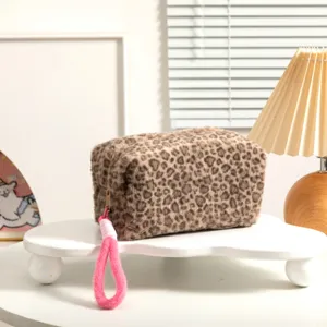 Detalle del neceser de peluche con estampado de leopardo y correa de mano rosa fucsia.