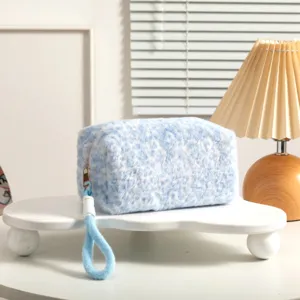 Vista de detalle del neceser de felpa suave con estampado de leopardo azul y asa de transporte