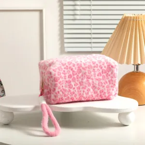 Primer plano de bolsa de maquillaje de felpa con estampado de leopardo rosa y asa suave.