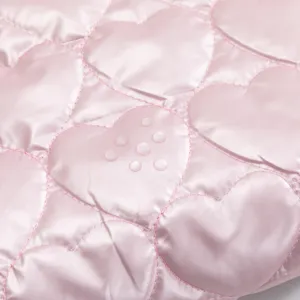 Detalle de tela rosa acolchada con corazones y revestimiento impermeable para maquillaje