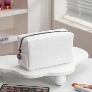 Detailweergave van witte wafelstructuur cosmetische tas op een decoratieve standaard