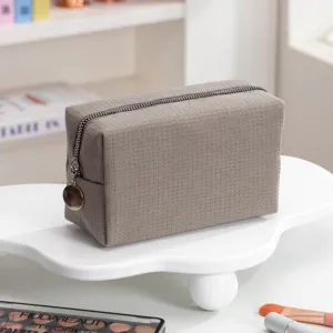 Macro detail van bruine make-up tas met wafeltextuur op witte decoratieve displaystandaard