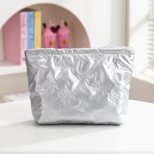 Primer plano detallado de un neceser plateado acolchado con elegantes patrones de lazos.