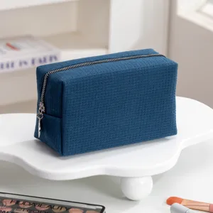 Close-up van de marineblauwe cosmetische tas met wafelstructuur en zilveren rits