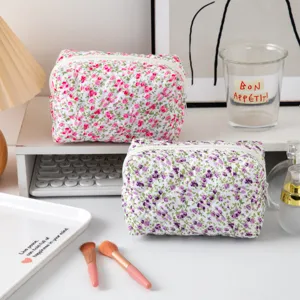 Gedetailleerd lifestylebeeld van twee gewatteerde bloemen make-uptassen op een bureau