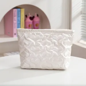 Detalle de neceser blanco acolchado con patrón de corazones y elegante acabado perlado