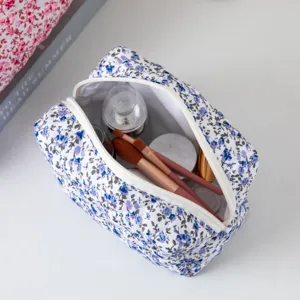 Detailopname van een gewatteerde make-uptas met bloemen met kwasten en cosmetica