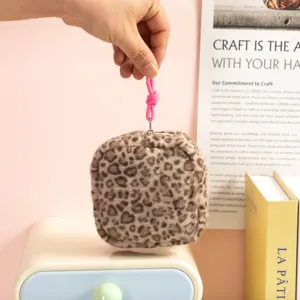 Mano sujetando una bolsa de felpa con estampado de leopardo de tamaño portátil