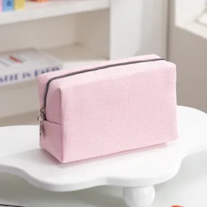 Gedetailleerde macro-opname van de roze wafelstructuur op deze reismake-up tas voor dames