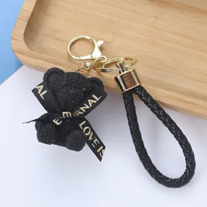 Close-up of black woven resin bear keychain with braided strap and gold clasp