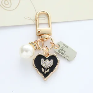 Detailed view of handmade heart keychain with pearl and engraved metal tag