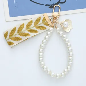 Detail view of pearl bead lanyard and embroidered ribbon on gold keychain