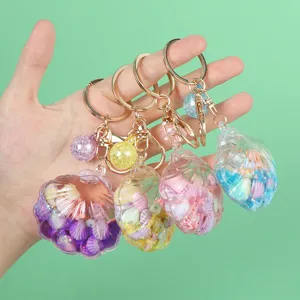 Close-up view of four colorful shell-shaped liquid quicksand keychains with gold rings