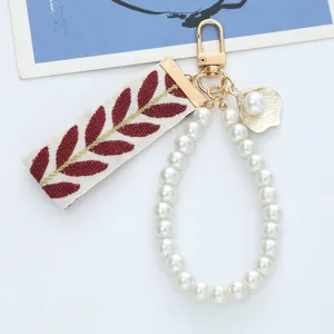 Detailed view of fresh woven strap keychain with pearl loop and golden leaf pattern