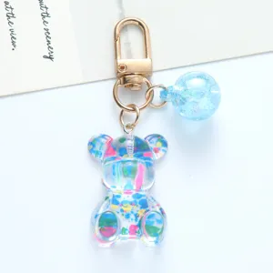 Detail view of a cute transparent acrylic bear keychain with vibrant colorful splatter patterns.