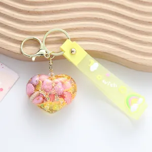 Detail of heart-shaped resin keychain filled with shells and glitter on yellow strap