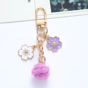 Detailed view of elegant golden keychain featuring sakura blossoms and a soft purple pom-pom