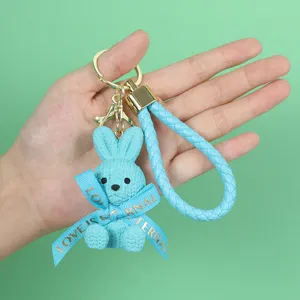 Detailed view of a light blue resin bunny keychain featuring a braided strap and bow
