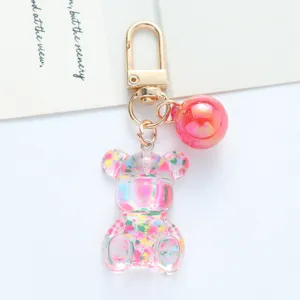 Close-up view of a colorful acrylic bear keychain with a pink gradient ball accessory.